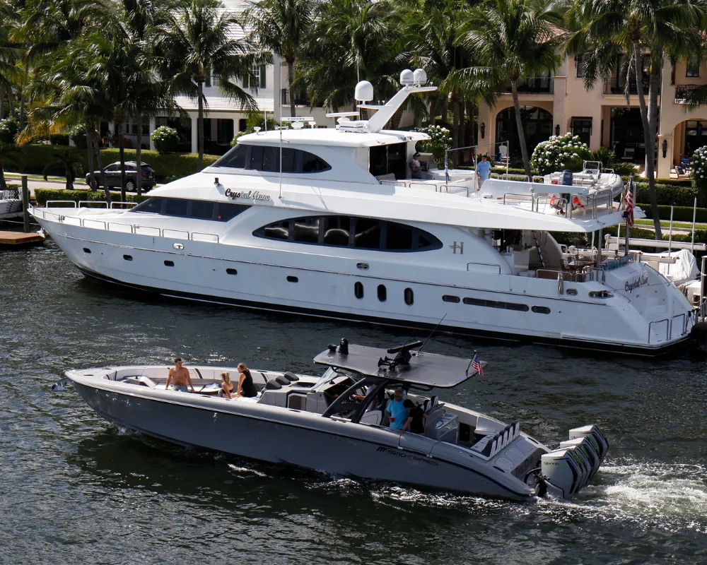 A center console passing by a big yacht in front of a house on a canal in Florida